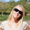 Woman wears black polarized vistana fit over sun glasses to shield her eyes from solar radiation.